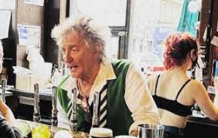 Pub patrons are surprised as Rod Stewart pulls drinks from behind the bar.